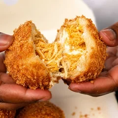 Mini bomba de frango empanada, aberta ao meio com frango desfiado